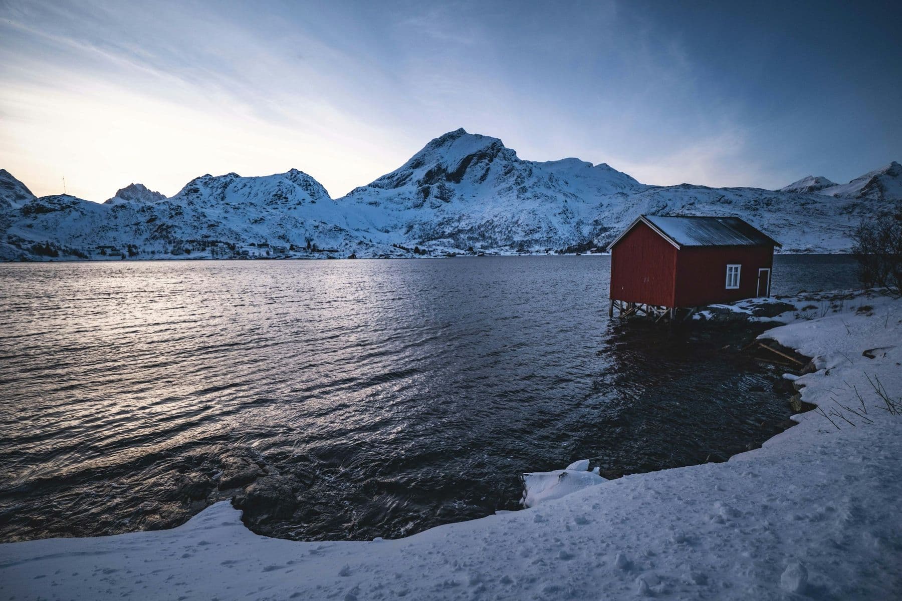 A red cabin on a mountain lake